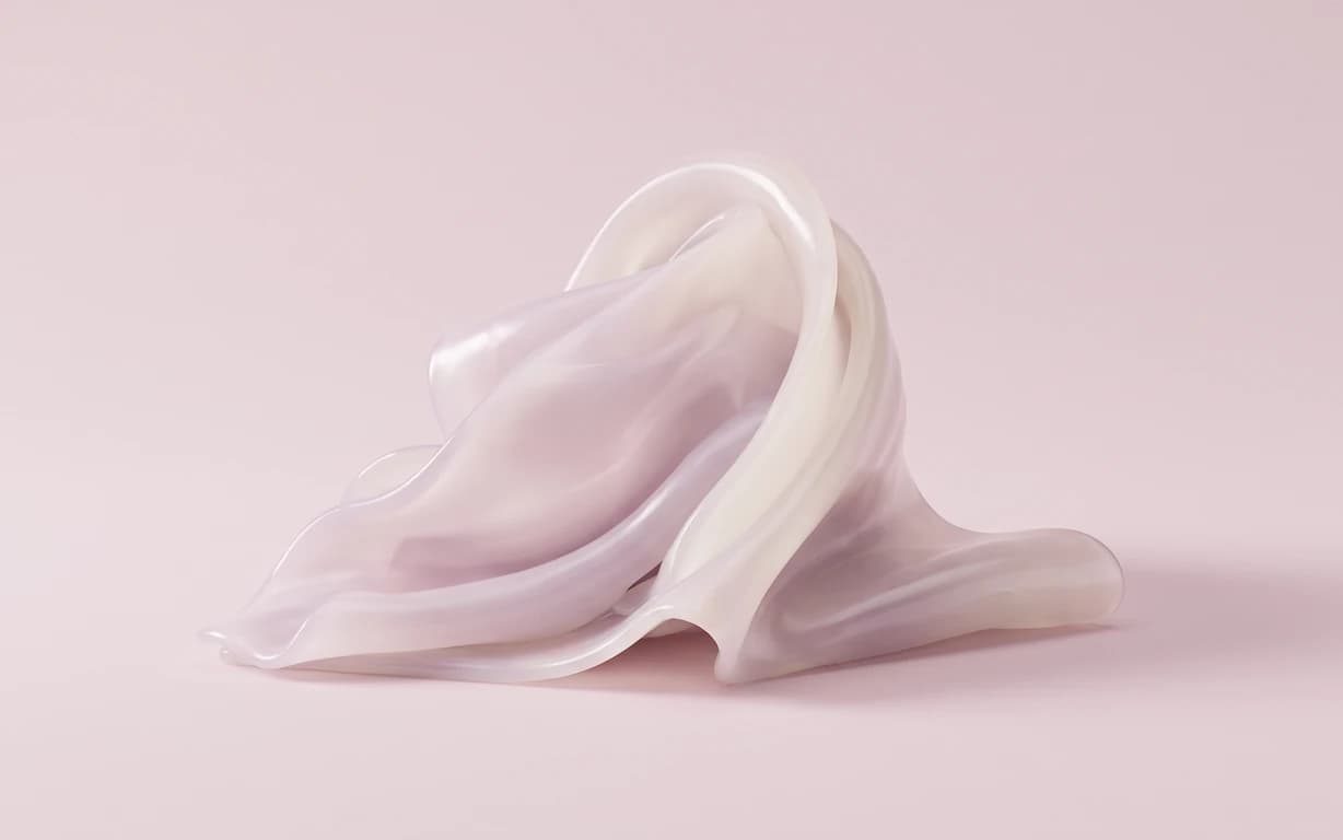 Soft translucent ivory and blush-lilac folds arranged as an abstract sculpture on a pale pink seamless surface.