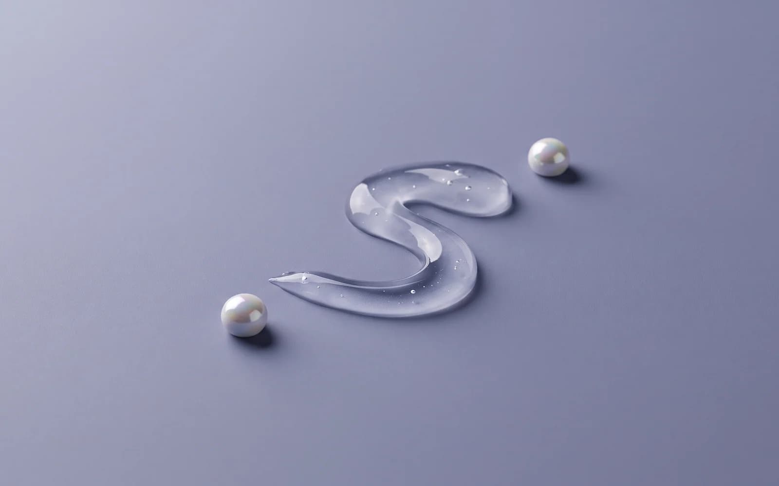 A clear S-shaped gel ribbon with two pearl-like beads on a slate-lilac surface.