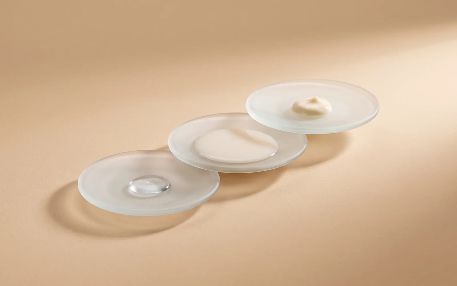 Three frosted glass dishes arranged diagonally with watery, milky and creamy textures.